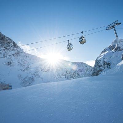 Ski lift over snowy alpine slopes with bright sunshine in the mountains